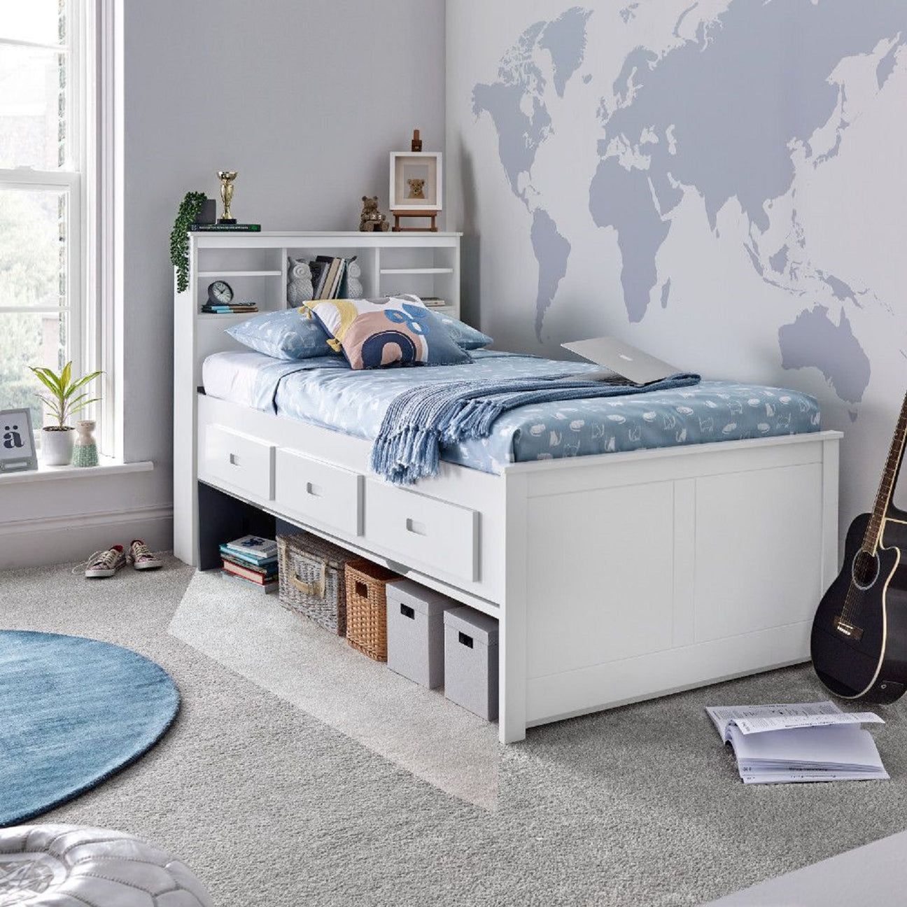 White bed with storage drawers in a room with a world map on the wall.