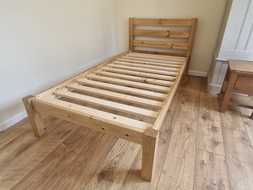 Wooden bed frame on a wooden floor with a neutral wall background