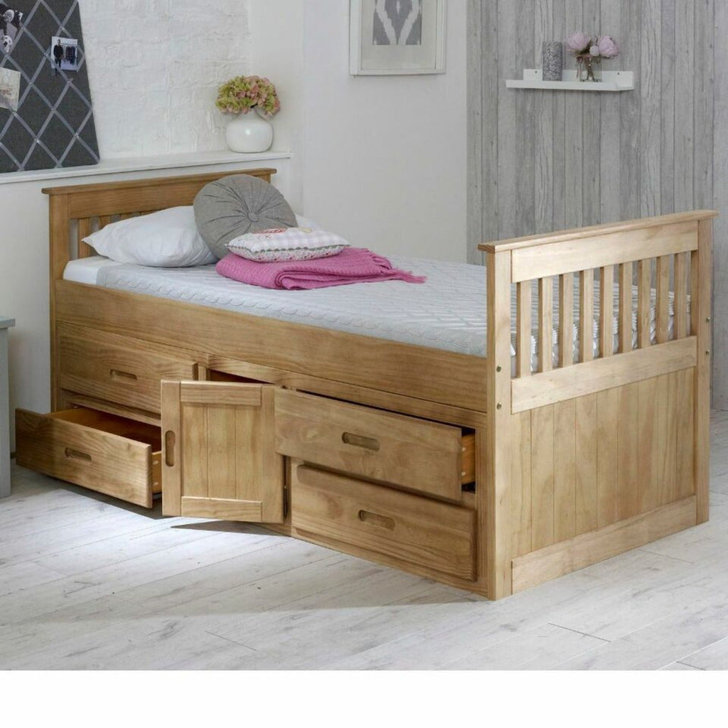 Captains Wooden Underbed Storage Bed - Captain's bed in waxed pine, doors and drawers slightly open, positioned at an angle in a grey bedroom - Beds4Us