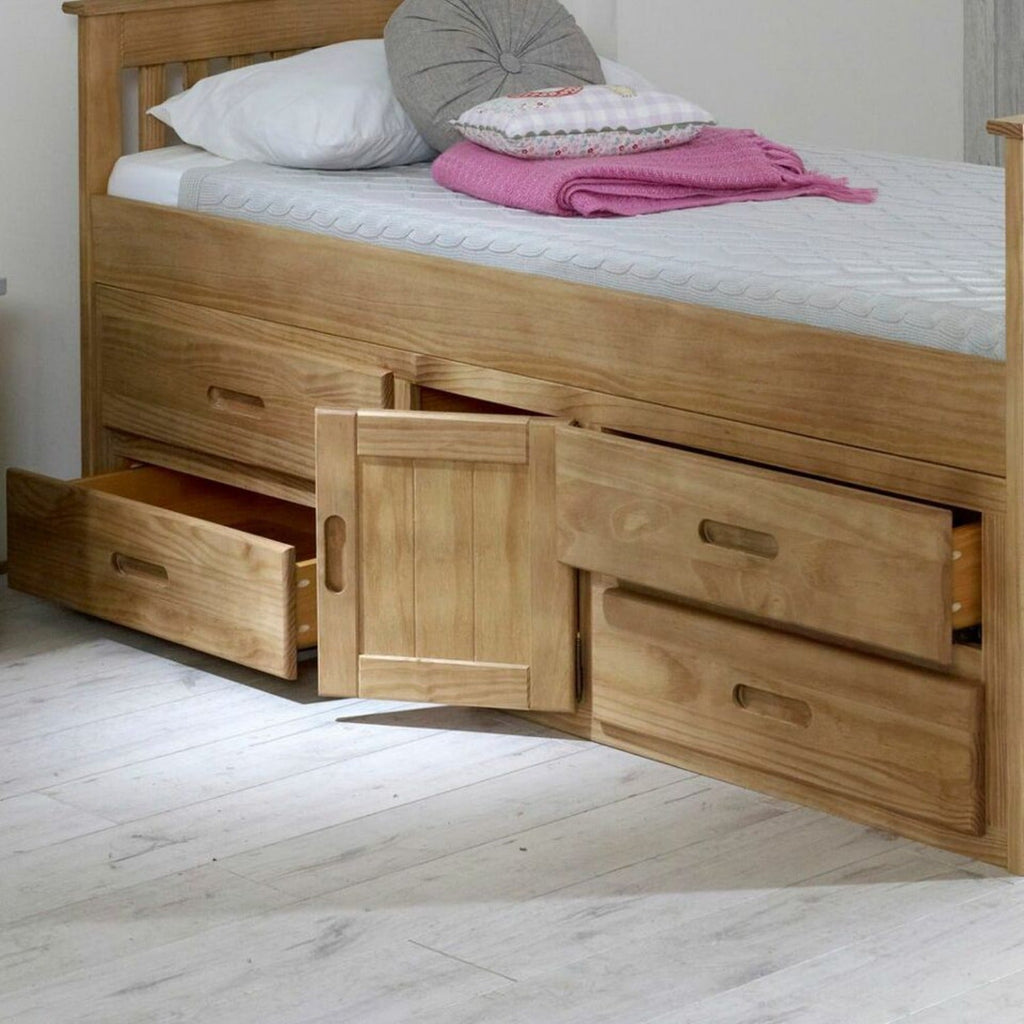 Captains Wooden Underbed Storage Bed - Close up of captain's bed in waxed pine, doors and drawers slightly open, positioned at an angle in a grey bedroom - Beds4Us