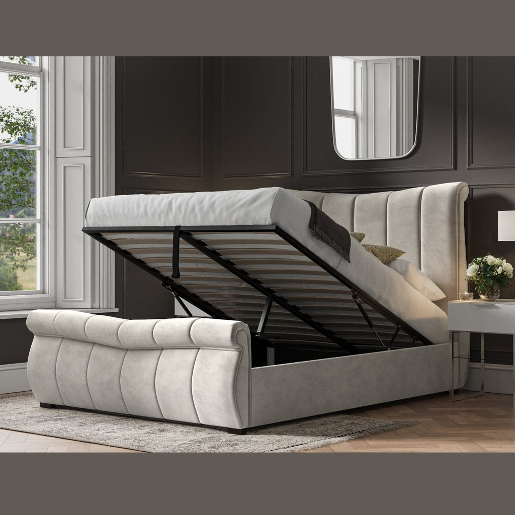 Bosworth Fabric Ottoman Storage Sleigh Bed  - Light grey sleigh ottoman bed frame positioned at an angle, ottoman base lifted up, in a dark modern room - Beds4Us